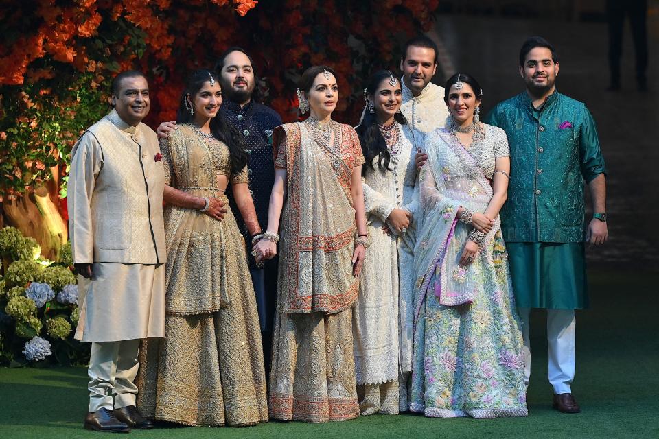 Indian billionaire Mukesh Ambani (L) along with his wife Nita (4L) pose with their elder son Akash (R), his wife Shloka (2R), daughter Isha (4R) her husband Anand Piramal (3R) and younger son Anant (3L) his fiancé Radhika Merchant (2L) during Anant's engagement ceremony in Mumbai on January 19, 2023.