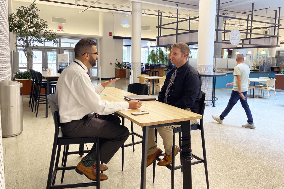 Brendan Horohoe, of Rochester, NY, seated at right, a Rochester City School District teacher applicant, is interviewed by Christopher Miller, the Rochester City School District's chief of human resources, during a recruitment event at the Mercantile On Main, in Rochester, NY, Wednesday, Aug. 17, 2022. Horohoe was applying for a position as a history teacher after moving from North Carolina. (AP Photo/Carolyn Thompson)