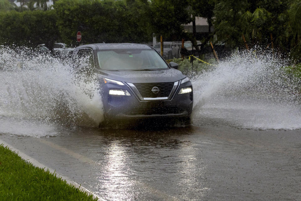 A car crosses the flooded road caused by heavy rain on North Bay Rd in Sunny Isles Beach, Fla., Tuesday, June 11, 2024. (David Santiago/Miami Herald via AP)