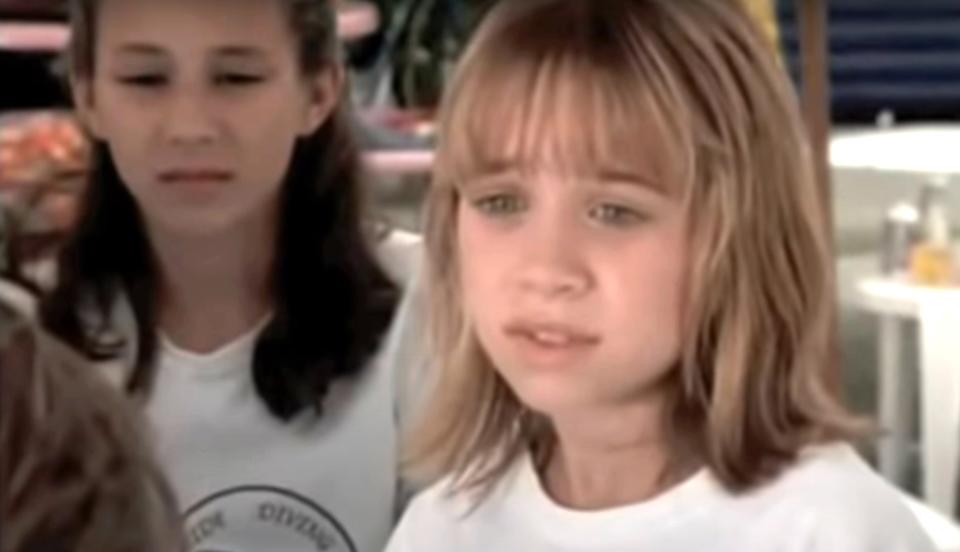 Close-up of a young Troian looking serious and standing behind one of the Olsen twins