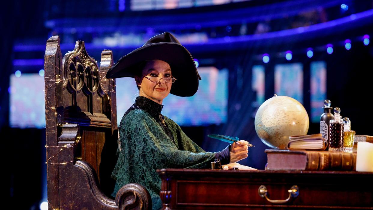 Sarah Hadland as Professor Minerva McGonagall sitting at a desk