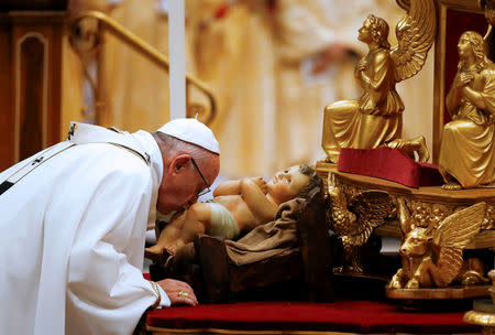 Pope Francis kisses a statuette of baby Jesus during the traditional midnight Mass in St. Peter's Basilica on Christmas Eve at the Vatican December 24, 2017. REUTERS/Tony Gentile