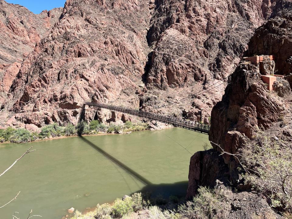 A river amid mountains with a bridge going over it.