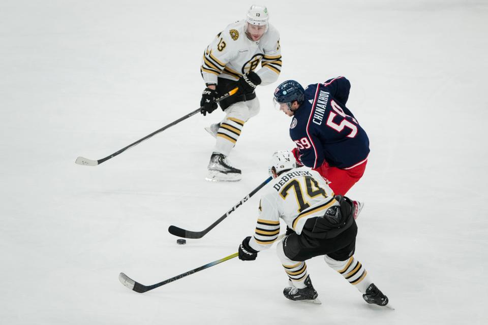 Nov 27, 2023; Columbus, Ohio, USA; Columbus Blue Jackets right wing Yegor Chinakhov (59) skates between Boston Bruins left wing Jake DeBrusk (74) and center Charlie Coyle (13) during the second period of the NHL game at Nationwide Arena.