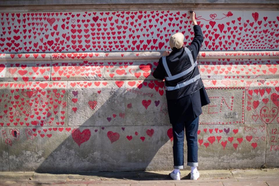 A volunteer adds hearts to the Covid memorial wall in Westminster, central London (Dominic Lipinski/PA) (PA Archive)