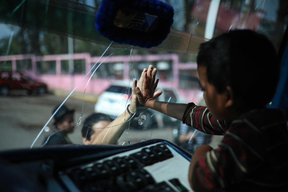 <p>A boy says goodbye to a friend through the windshield of a bus that will carry him to Mexico City from the sports club where Central American migrants traveling with the annual “Stations of the Cross” caravan had been camping out in Matias Romero, Oaxaca State, Mexico, Thursday, April 5, 2018. (Photo: Felix Marquez/AP) </p>