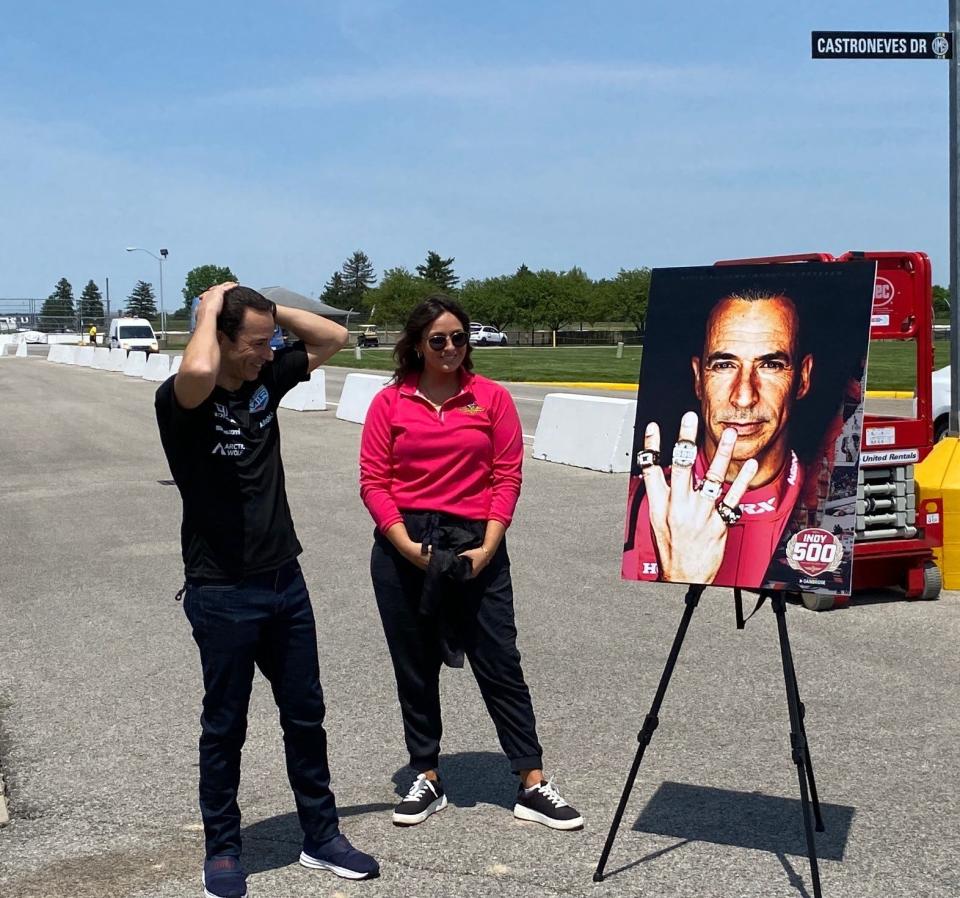 Helio Castroneves reacts to seeing his face on this year's Indy 500 program, designed by Grace Keller (center). Castroneves is the first defending winner to have his face on the cover of the historic commemorative item.