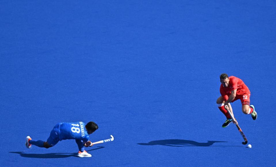 England’s David Condon (R) jumps to block a shot from India’s Nilakanta Sharma during the Pool B hockey match between England and India (AFP via Getty Images)