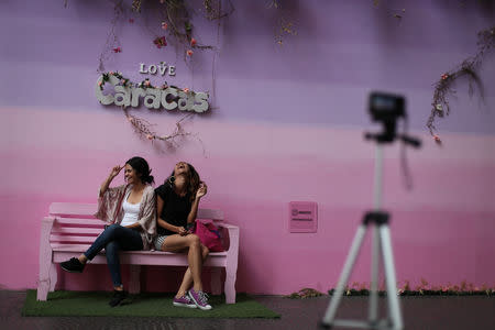 Ana Gabriela Alzola and Deniali Vega pose for a photograph at a backdrop used by customers to take pictures inside a mall in Caracas, Venezuela, March 24, 2019. REUTERS/Ivan Alvarado