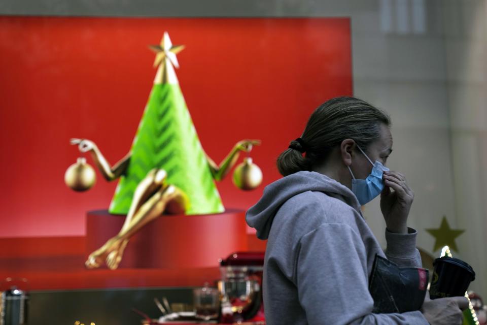 A woman adjusts her face mask as she passes a Christmas decorated shop front window in Athens, Greece, Monday, Nov. 29, 2021. Greece has recorded a spike in deaths and infections related to COVID-19 this month, amid heightened concerns in Europe due to the Omicron variant. The Greek government has ruling out the prospect of a general lockdown. (AP Photo/Thanassis Stavrakis)