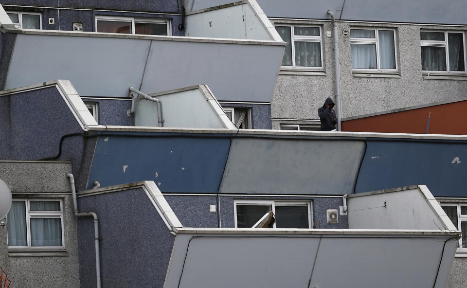 A man stands on a balcony at a block of apartments on the Broadwater Farm estate in north London, Britain, December 30, 2015. Oliver Letwin, British Prime Minister David Cameron's policy chief, apologised on Wednesday after a newly released memo from 30 years ago revealed he had blamed poor morals in the black community for the 1985 riots in the Broadwater Farm estate and said any investment would be wasted on discos and drugs.  REUTERS/Peter Nicholls