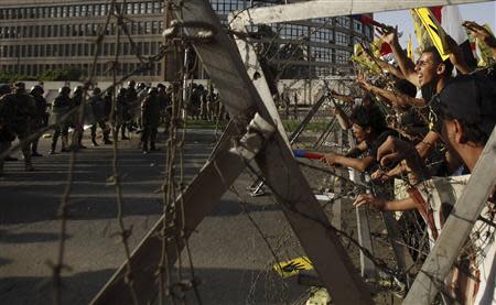 Members of the Muslim Brotherhood and supporters of ousted Egyptian President Mohamed Mursi shout slogans next to barbed wire as army soldiers and the riot police look on, during a protest against the military, at Cairo's Nasr City district, October 4, 2013. REUTERS/Amr Abdallah Dalsh