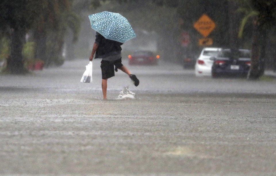 A person walks down a flooded street in Hallandale Beach, Fla., Saturday June 4, 2022, on Saturday, June 4, 2022. (Mike Stocker/South Florida Sun-Sentinel via AP)