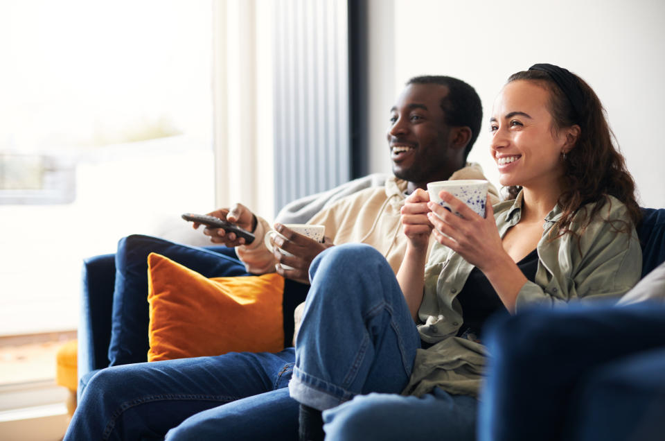 Young couple relaxing on sofa at home watching or streaming tv together