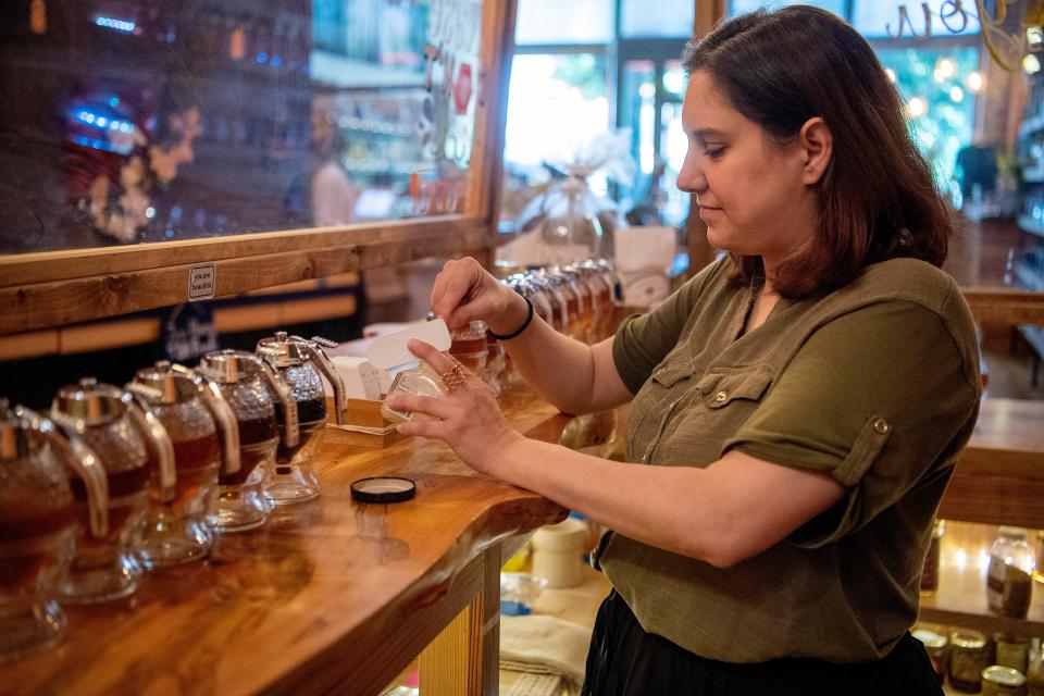 Teresa Tribolet, assistant manager of the Asheville Bee Charmer, scoops honey for sampling May 11, 2022.