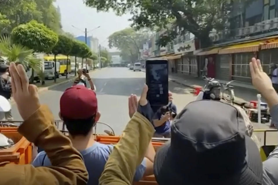In this image made from video, anti-coup protesters flash the three-fingered salut at police, rear, in Yangon, Myanmar, Saturday, Feb. 27, 2021. Myanmar police on Saturday moved to clear anti-coup protesters from the streets of the country's biggest city Yangon. (AP Photo)