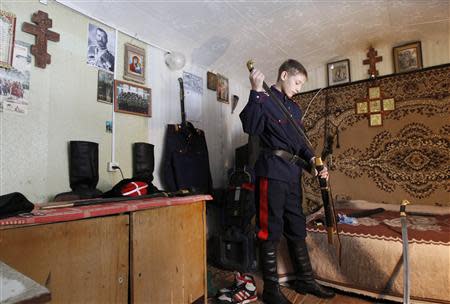 Russian Cossack Vyacheslav Timoshenko, 13, sheathes a sword after juggling it, in the town of Krasny Oktyabr on the outskirts of the southern Russian city of Volgograd, January 5, 2014. REUTERS/Vasily Fedosenko