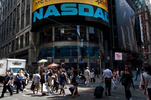 People are seen walking past the Nasdaq exchange in Time Square, New York, in June. Facebook reports its first earnings as a public company on Thursday in an announcement that will be closely watched for signs of whether the social media giant can deliver on its financial promise