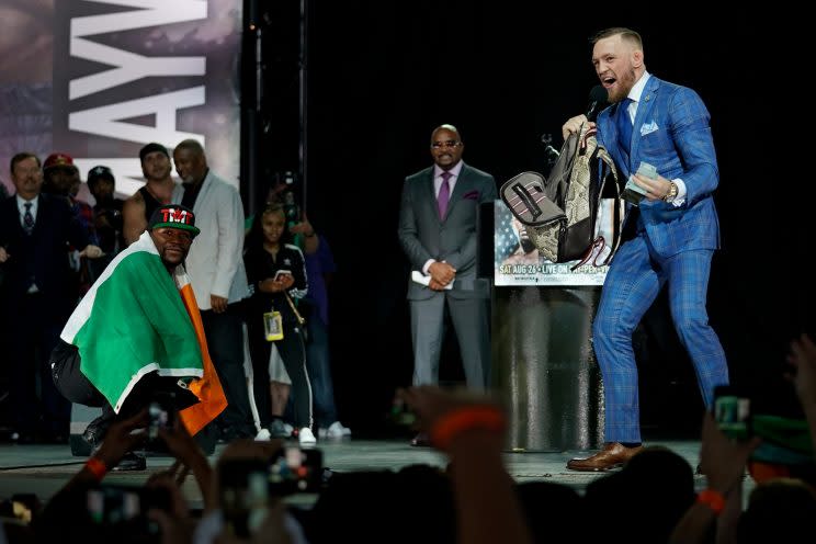 Floyd Mayweather (L) poses with the Irish flag while Conor McGregor rifles through Mayweather's backpack. (Getty)