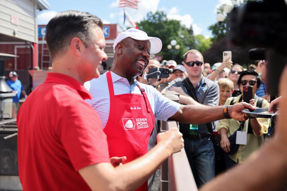 U.S. Senator and Republican presidential candidate Tim Scott (R-SC) hands out grilled pork chops at the Iowa State Fair (REUTERS)