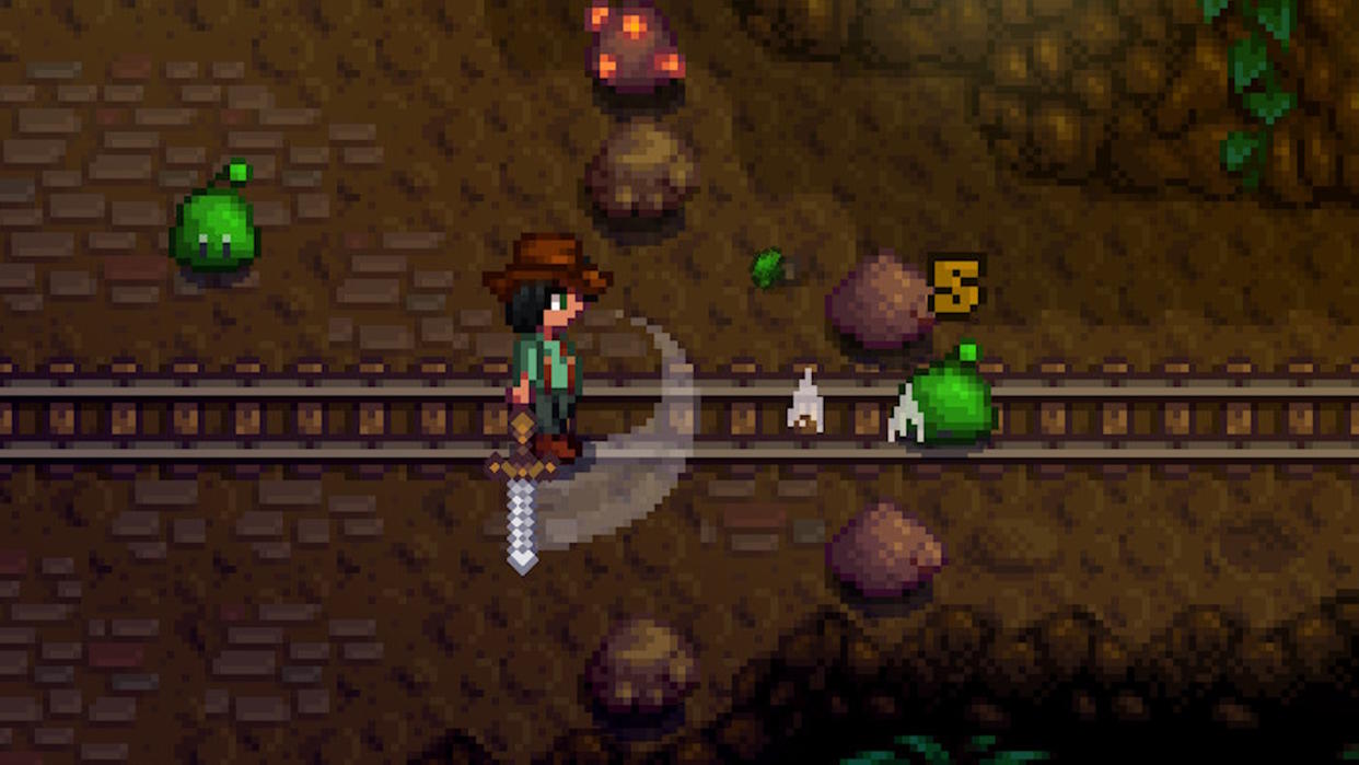  Stardew Valley screenshot - player swinging a sword in a fight against a monster in a mine. 