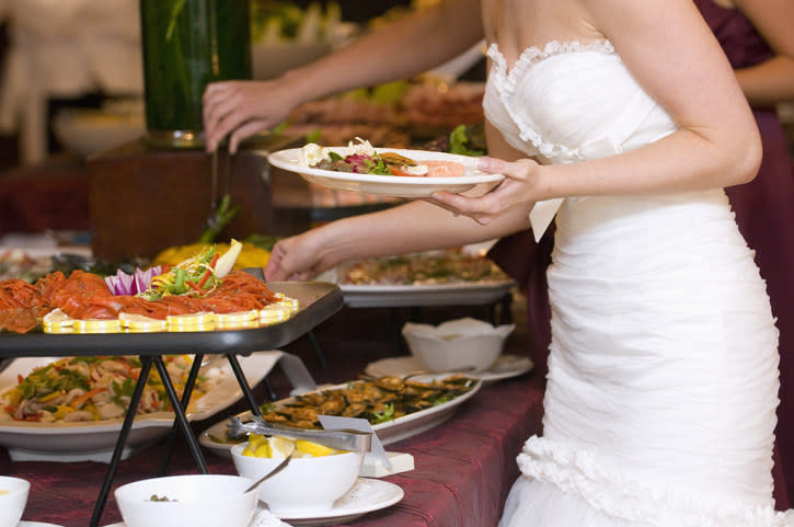A bride serving herself a plate at the wedding reception.