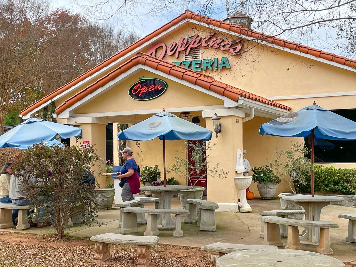 A staff member brings an order to customers in the patio dining area at Peppino's Pizzeria in Athens, Ga. on Thursday, Nov. 16, 2023.
