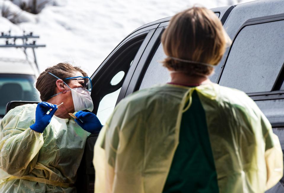 Infection Control's Amy Carter, left, and respiratory therapist Kim Thompson perform a real-time test for coronavirus on patients with appointments in Colorado outside the Aspen Volunteer Fire Department's Aspen Village Location on March 12, 2020. (Kelsey Brunner/The Aspen Times via AP)