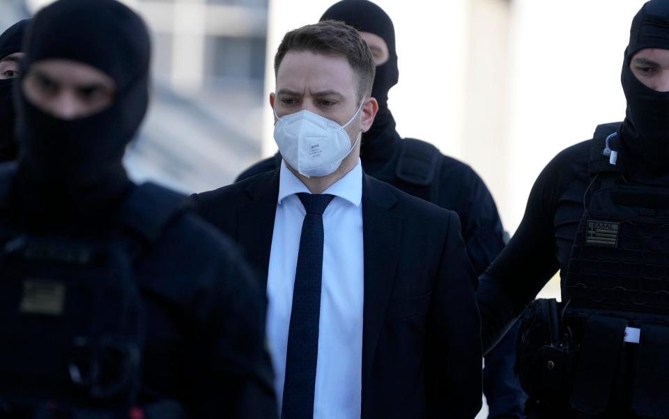 Babis Anagnostopoulos, a Greek pilot and flight instructor, center, escorted by policemen arrives at a court in Athens, Greece - Thanassis Stavrakis/AP