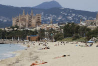 In this May 25, 2020 photo, people sit on the beach in Palma de Mallorca, Spain. Spain's Balearic Islands will allow for thousands of German tourists to fly in from June 15 for a two-week trial of tourism under new regulations against the spread of the new coronavirus. (Isaac Buj/Europa Press via AP)
