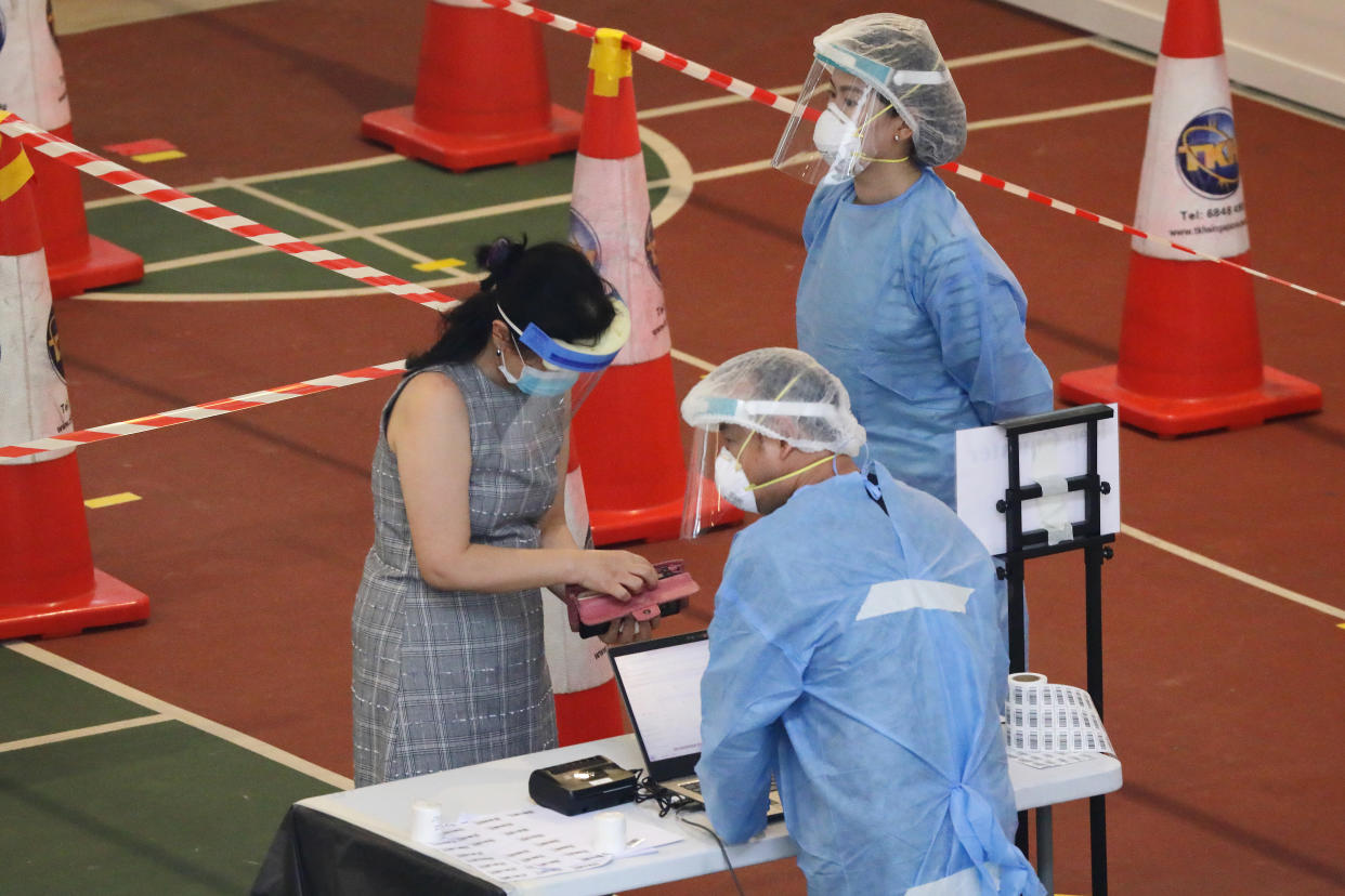 Healthcare workers dressed in personal protective equipment attend to a resident during registration for a mandatory swab test at a temporarily COVID-19 testing centre on 20 June. (PHOTO: Getty Images)