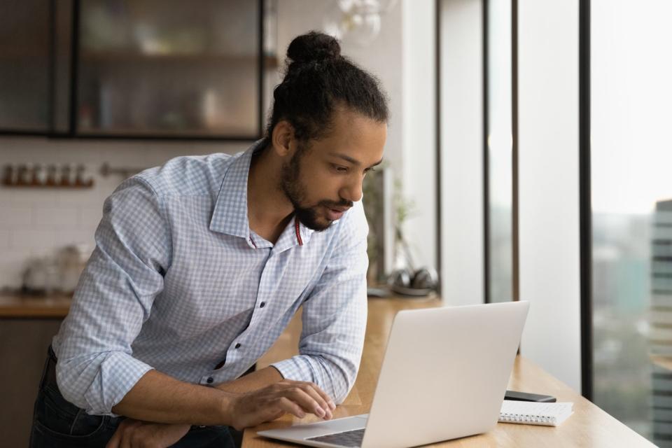 An investor studies something on a laptop in a kitchen.