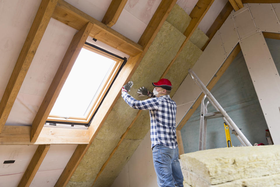 Man installing thermal roof insulation layer - using mineral wool panels. Attic renovation and insulation concept