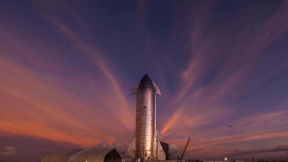 The sky begins to light up before sunrise over a prototype of the SpaceX Starship at the SpaceX launch facility in Texas, near Boca Chica.