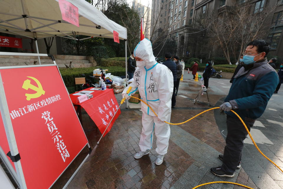 Government workers disinfect a work post with the sign "Model Community Party Post" outside a residential block in Xi'an city in northwest China's Shaanxi province Monday, Jan. 3, 2022. Authorities in the northern Chinese city of Xi'an say they can provide food, health care and other necessities for the roughly 13 million under an almost two-week old lockdown. But some residents describe difficulties obtaining supplies and frustration and the economic impact on the city that is home to the famed Terracotta warriors, along with major industries. (Chinatopix Via AP)