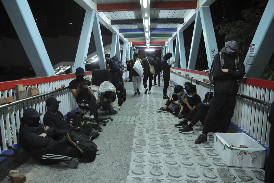 Protesters rest on a bridge in Hong Kong, early Saturday, Nov. 9, 2019. A Hong Kong university student who fell off a parking garage after police fired tear gas during clashes with anti-government protesters died Friday in a rare fatality in five months of unrest, fueling more outrage against authorities in the semi-autonomous Chinese territory. (AP Photo/Kin Cheung)