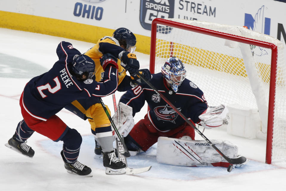 Columbus Blue Jackets' Elvis Merzlikins, right, makes a save against Nashville Predators' Roman Josi, center, as Andrew Peeke defends during the third period of an NHL hockey game Thursday, Feb. 18, 2021, in Columbus, Ohio. The Blue Jackets beat the Predators 3-0. (AP Photo/Jay LaPrete)