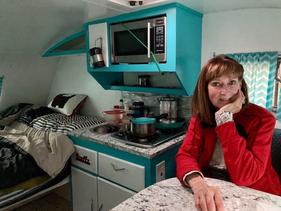Tim's wife Susan at home in the 64 Scotty, with small kitchen behind her.