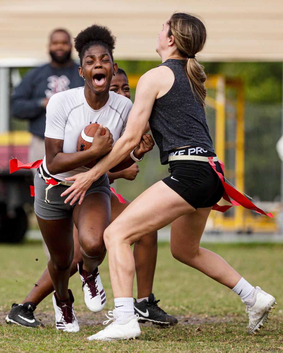 Delana Osnac, left, a member of the girls flag football team reacts while running the ball during a scrimmage at the school on Monday, Feb. 12, 2024. Zoey OÕNan comes in to grab the flag.