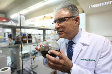 Professor Mohammad Mroueh holds a wild carrot oil in a lab room at the Byblos campus of the Lebanese American University, in Byblos, Lebanon August 1, 2018. Picture taken August 1, 2018. REUTERS/Aziz Taher