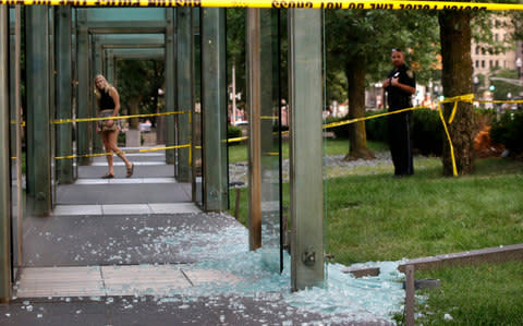 A passerby, left, and a law enforcement official, right, stand near broken glass at the New England Holocaust Memorial on Monday, Aug. 14, 2017, in Boston - Credit: AP