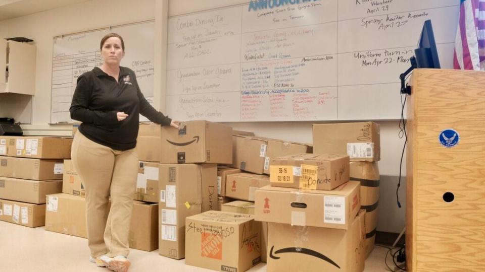 Sgt. Kathryn Manning stands by boxes full of JROTC gear slated to be donated at the end of the year on April 22, 2024. The whiteboard behind her lists her students’ academic and military achievements. (Claire Stremple/Alaska Beacon)