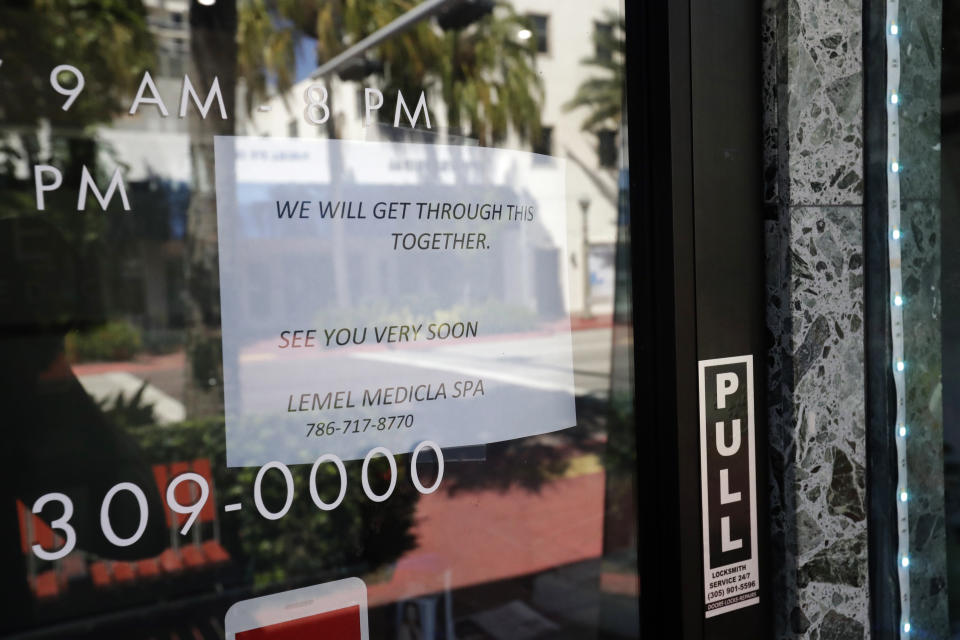 A sign indicates a closed business Saturday, March 21, 2020, in downtown Surfside, Fla. Miami-Dade County's mayor on Thursday ordered all beaches, parks and "non-essential" commercial and retail businesses closed because of the coronavirus pandemic. (AP Photo/Wilfredo Lee)