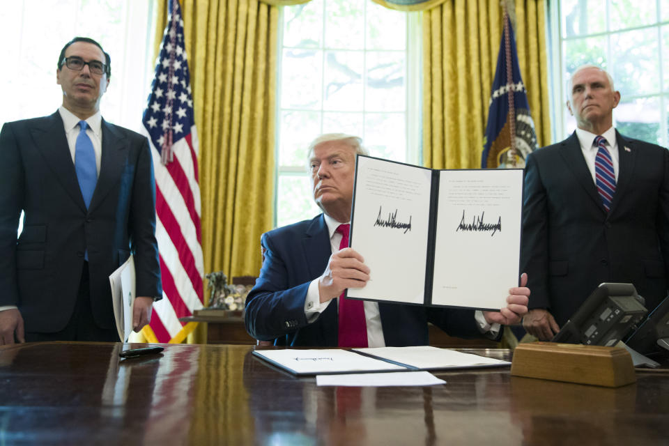 President Donald Trump holds up a signed executive order to increase sanctions on Iran, in the Oval Office of the White House, Monday, June 24, 2019, in Washington. Trump is accompanied by Treasury Secretary Steve Mnuchin, left, and Vice President Mike Pence. (AP Photo/Alex Brandon)