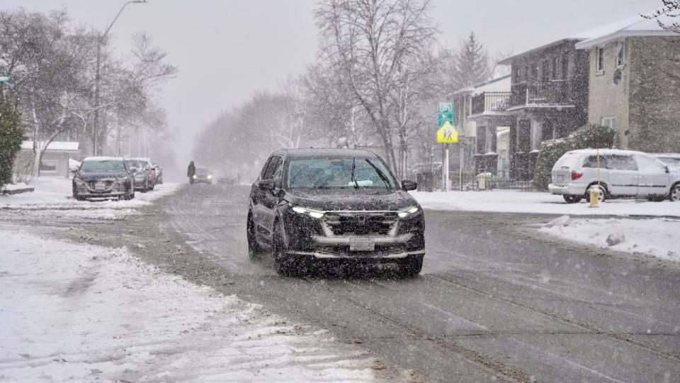 People drive and walk on a residential Ottawa street on April 4, 2024, the second day of a spring storm.