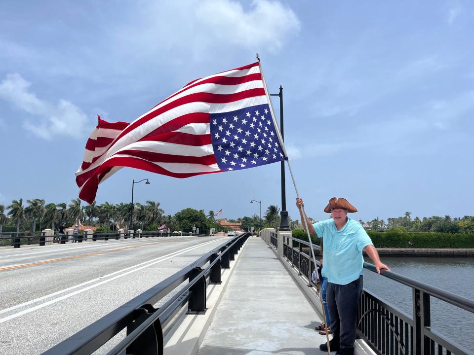 Ben Polluck, who was a protestor on January 6, holds a flag upside down outside Mar-a-Lago.