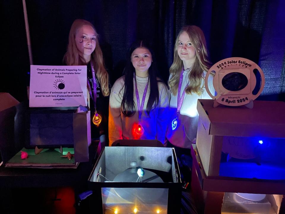 Maria Hamilton, Ella Harris and Onika Gourdine, students at Max Aitken Academy in Miramichi, show an eclipse model they built at a science fair on Thursday.