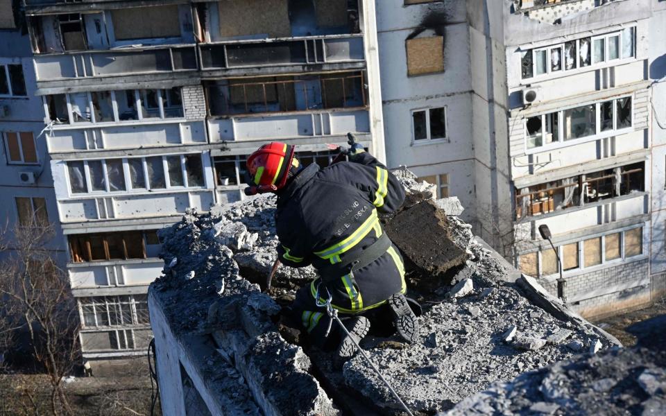 A man removes debris from a residential building during renovations of an appartment block, partially destroyed by shelling, in the outskirt of Kharkiv - SERGEY BOBOK/AFP