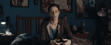 Pete Davidson playing video games with a distant look on his face