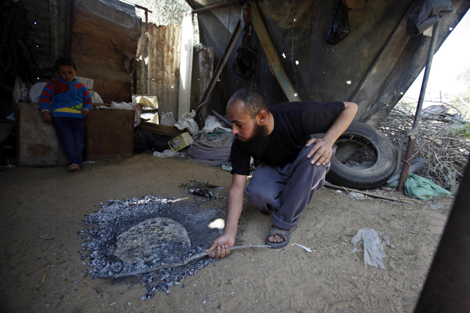 In this Monday, March 18, 2013 photograph, Bassam el-Shaka covers a loaf of bread with ash charcoal as he prepares a dish called "libbeh" in Rafah, southern Gaza Strip, Monday, March 18, 2013. Gaza cuisine is Mediterranean-based, relying on olive oil, fresh vegetables, herbs and grains. "The Gaza Kitchen" is being praised by celebrity chefs like Anthony Bourdain for showcasing a unique, fiery variation of Mediterranean cuisine kept alive through blockade, war and impoverishment. (AP Photo/Adel Hana)